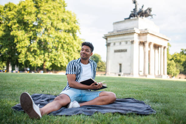 istock Relaxed Mixed Race Man Enjoying a Book in a London Meadow 1160666898