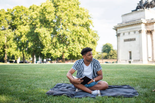 istock Relaxed Mixed Race Man Enjoying a Book in a London Meadow 1160666903