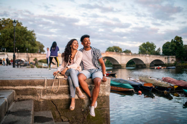 pares de sorriso que sentam-se na terraplenamento em richmond upon thames - city break - fotografias e filmes do acervo