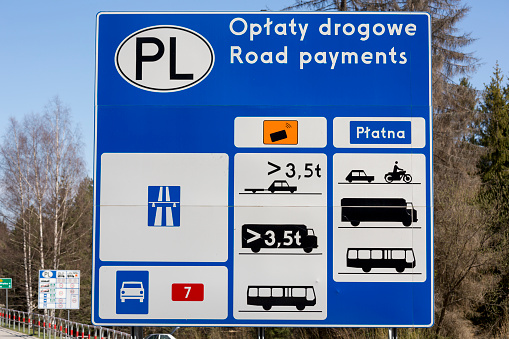 A country road leads from Slovakia into Poland, in Western Europe.  A multi-faceted road warning sign and information sign conveys details about driving requirements in Poland.