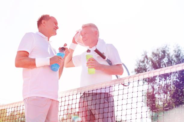 istock Low angle view of men talking while standing by tennis net against clear sky on sunny day 1160671787