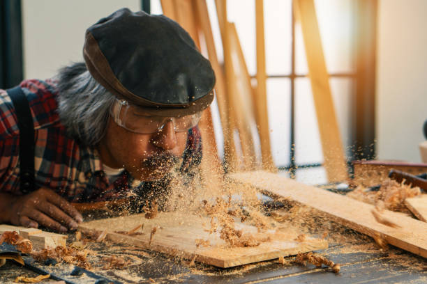 istock senior carpenter blowing wood dust in making woodwork for hobby 1160672669