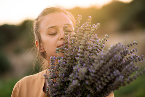 Woman has closed eyes and holds a bouquet of lavender