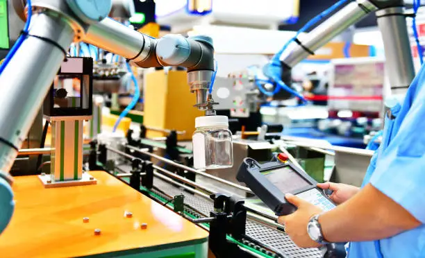 Engineer check and control automation robot arms arranged glass water bottle on Automatic industrial machinery equipment in production line factory