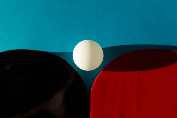 A close up of table tennis bats and ball on a blue background with copy space.