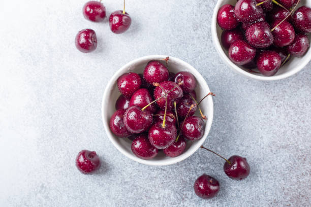 istock Fresh ripe red cherries in a white bowl on a gray stone background Copy space 1160690033