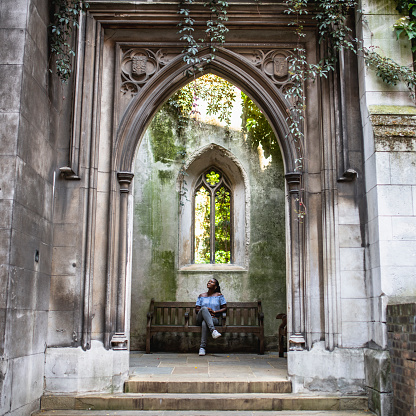 Adult African woman admiring the beauty and the scale of a church called St Dunstan in the East in London