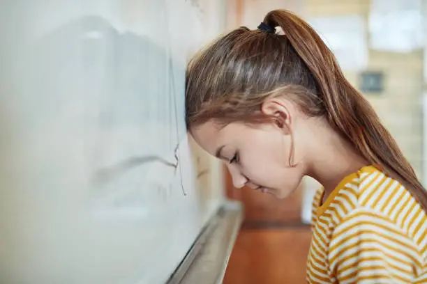 Shot of a young girl leaning against a board in a classroom at school