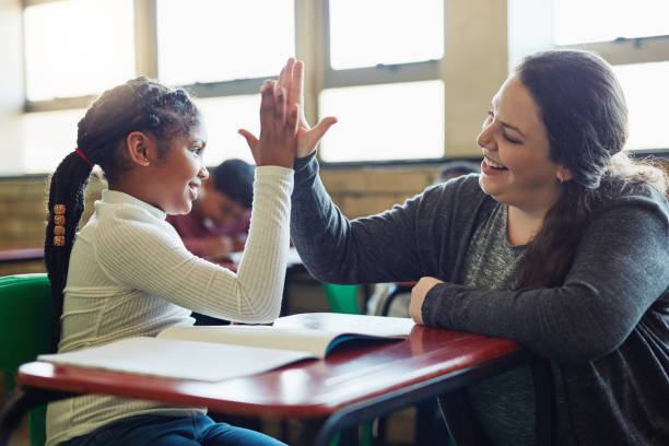 Nothing fosters learning like encouragement Shot of a young girl giving her teacher a high five in a classroom encouragement stock pictures, royalty-free photos & images