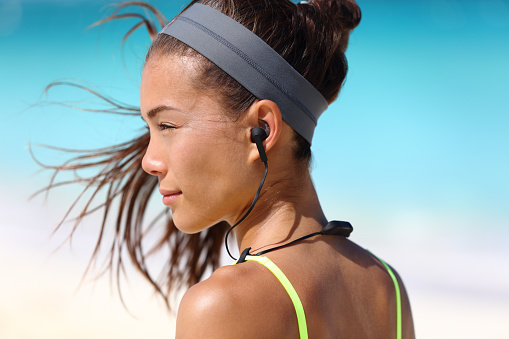 Chica de fitness con auriculares inalámbricos deportivos en la oreja photo
