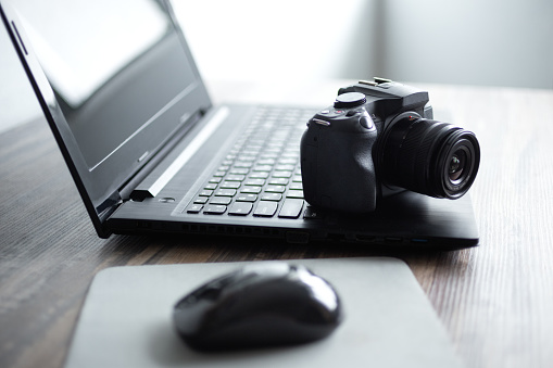 Photographer or stock photography concept, digital black camera near laptop on desk workstation