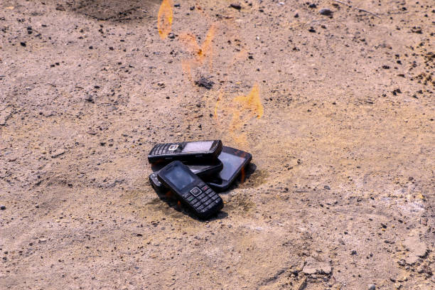 istock burnt mobile phones on textural concrete background. Concept: Danger of using low-quality cell phones. 1160695924