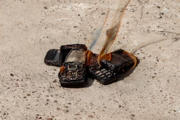 istock burnt mobile phones on textural concrete background. Concept: Danger of using low-quality cell phones. 1160695968