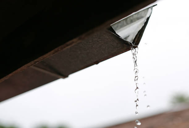 istock Rain pouring off roof with rays of sunlight. 1160696667