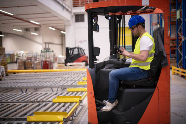 trabajador de almacén en carretilla elevadora esperando a que el camión entregue mercancías. - machine operator fotografías e imágenes de stock