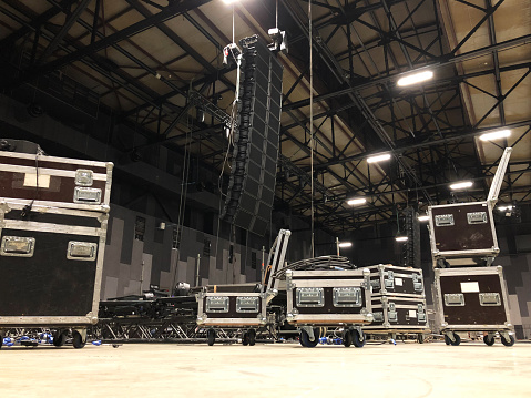 Installation of professional sound speakers, line array, light, video and stage equipment for a concert. Tech zone with flight cases.