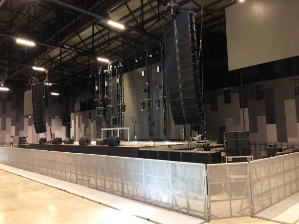 istock Installation of professional sound speakers, line array, light, video and stage equipment for a concert. Metal concert barriers in front of stage. 1160702453