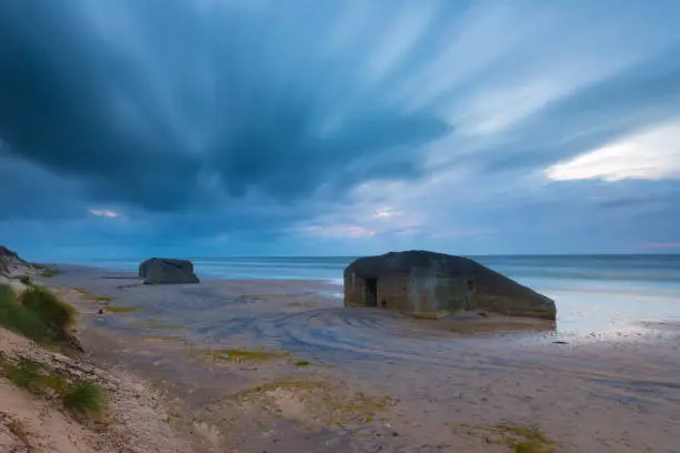Long exposure of old bunker fortifications on a sandy beach.