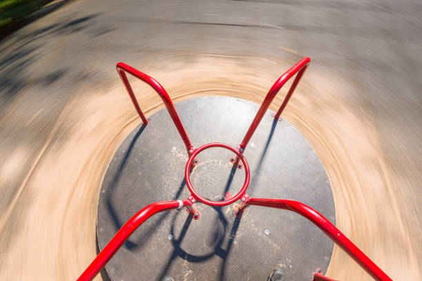 Teenagers sitting on chain carousel or chair swing ride. The teenagers are enjoying the carousel ride. The photo is motion blurred and the camera is following the three teenagers.\nShot with Canon R5