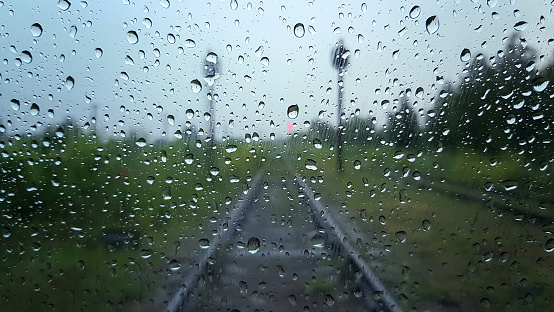 Raindrops on a window with a blurred railway road background.