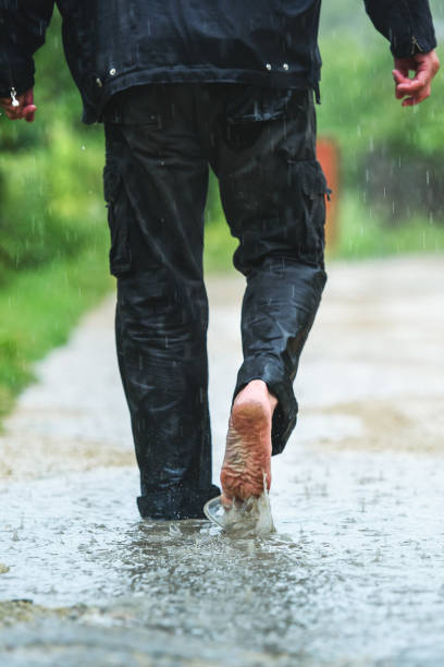 istock A man in the rain is barefoot in puddles 1160711165
