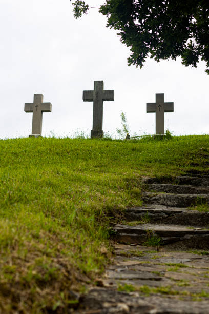 trois croix au sommet d'une colline dans un cimetière - cemetery crossing green grass photos et images de collection