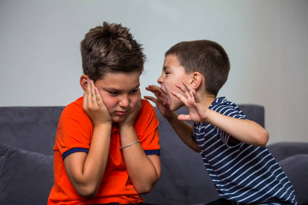 enfants de querelle - garçon criant à son frère. enfant criant fort. petit enfant tenant les mains près de la tête et effraie son frère - conflict face to face child arguing photos et images de collection