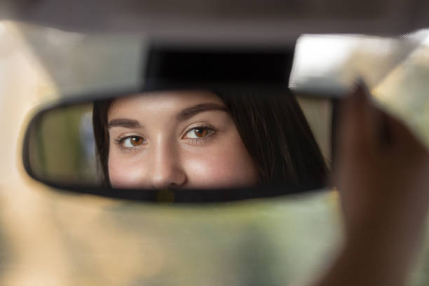 istock Girl looking in car rear view mirror 1160722820