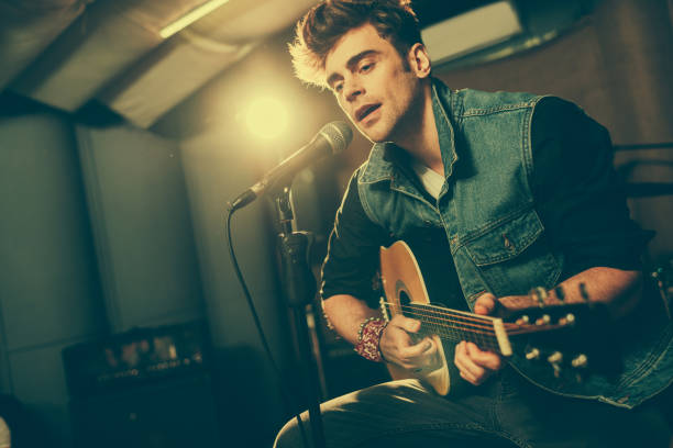 istock handsome singer singing in microphone while playing acoustic guitar 1160727002