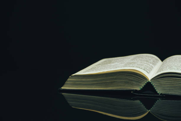 istock Open Holy Bible on a black glass table dark background 1160733312