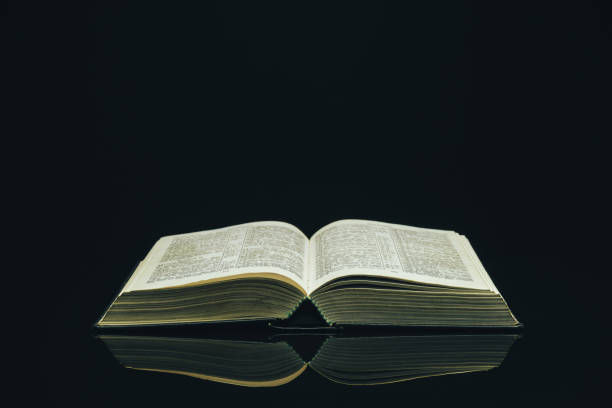 istock Open Holy Bible on a black glass table dark background 1160733477