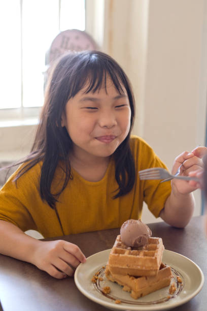istock Smiling girl eating waffles 1160733544