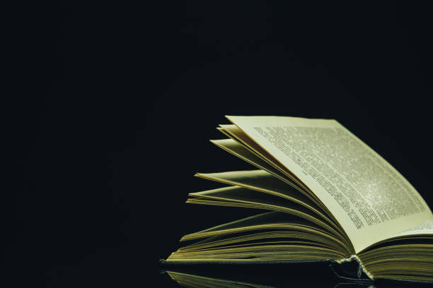 istock Open Holy Bible on a black glass table dark background 1160734687