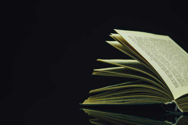istock Open Holy Bible on a black glass table dark background 1160734959