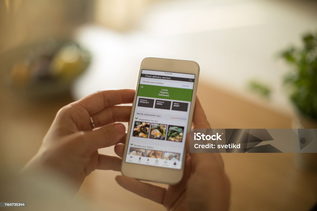 Woman using meal delivery service through mobile app. Woman is using mobile phone to order healthy organic veggies. She want to prepare healthy meal Mobile Phone Stock Photo