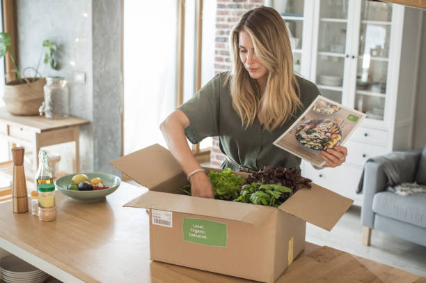 Woman got package from meal delivery service. Woman is received box loaded with organic vegetables from delivery service. She is up to make some fantastic vegan meal food delivery stock pictures, royalty-free photos & images