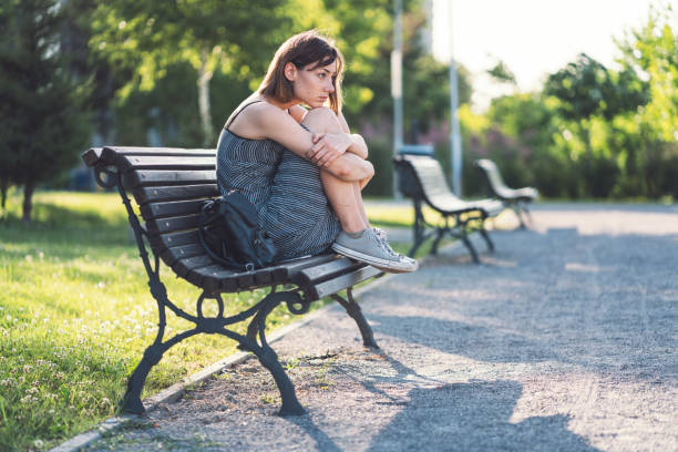istock Sad looking woman sitting in the park 1160735524