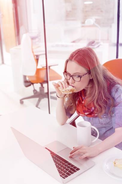 istock Businesswoman using touchpad of laptop while having breakfast in office 1160735826