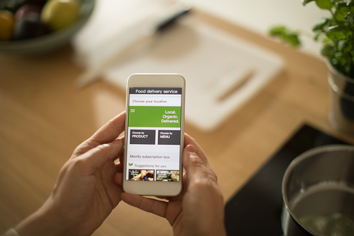 Woman is using mobile phone to order healthy organic veggies. She want to prepare healthy meal