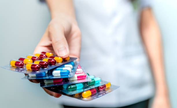 Pharmacist or doctor hand holding pack of antibiotic capsule pills and giving patient or people. Antibiotic drug overuse. Antimicrobial drug resistance. Community pharmacist. Drugstore background. Pharmacist or doctor hand holding pack of antibiotic capsule pills and giving patient or people. Antibiotic drug overuse. Antimicrobial drug resistance. Community pharmacist. Drugstore background. antibiotic stock pictures, royalty-free photos & images