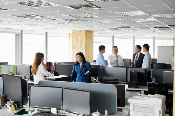 istock Business people discussing amidst desks in office 1160741993