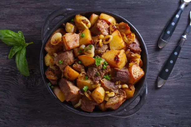 Tasty food: succulent beef with fried potatoes, onion and garlic. Country-style roasted potatoes with meat