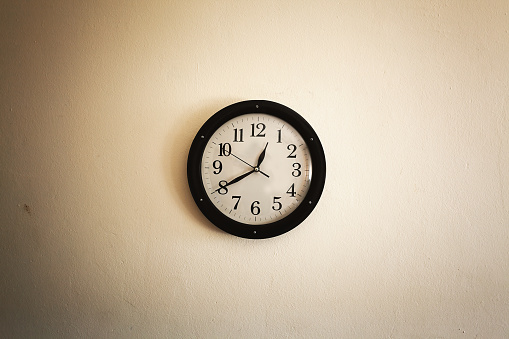 Old vintage style clock on old white wall.