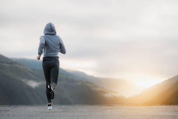 disparado de uma mulher adulta bonita que funciona no nascer do sol. - running jogging road exercising - fotografias e filmes do acervo