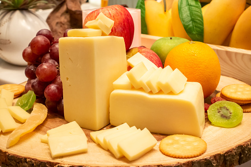 edam cheese with variety of fruit and cracker on wooden plate in buffet line