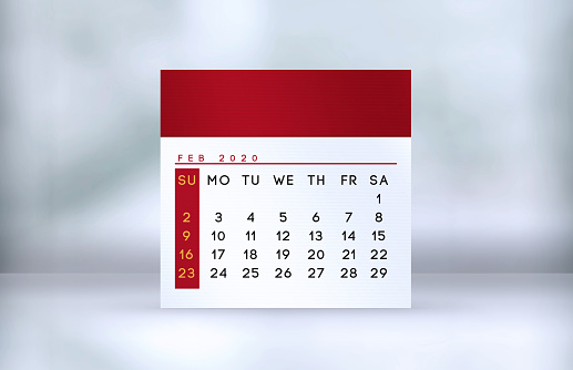 Red February desk calendar stands on the table with shadow