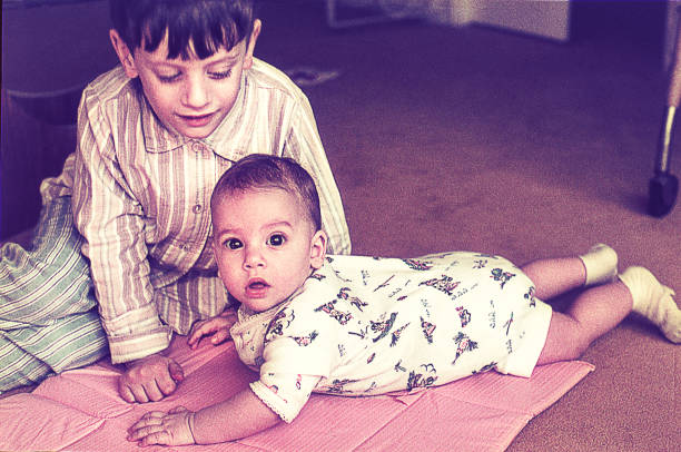 Big brother with baby sister at home Vintage photo of a boy with her baby sister on the floor at home. sister photos stock pictures, royalty-free photos & images