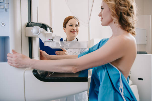 smiling radiologist standing near patient while making mammography diagnostics on x-ray machine smiling radiologist standing near patient while making mammography diagnostics on x-ray machine radiologist photos stock pictures, royalty-free photos & images