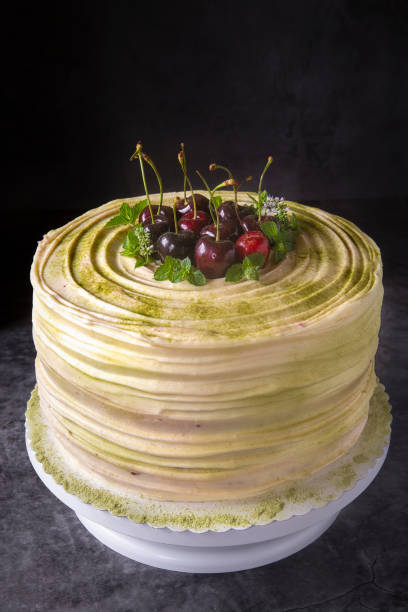 Cherry cake decorated with large cherry on a dark background. Festive pastries and a sweet table. Summer berries and desserts. Confectionery preparation.