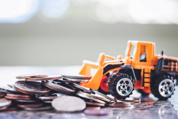 The yellow toy bulldozer with pile of coins against blurred background for saving money, investment, business and finance concept The yellow toy bulldozer with pile of coins against blurred background for saving money, investment, business and finance concept deposit bottle stock pictures, royalty-free photos & images